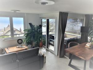 een woonkamer met een bank, een tafel en ramen bij Wonderful view of Lake Geneva in Chardonne
