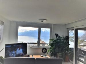 a living room with a couch and large windows at Wonderful view of Lake Geneva in Chardonne