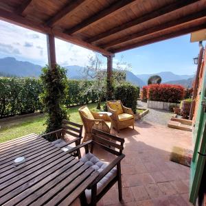 un patio con 2 bancos, mesa y sillas en Agriturismo Tenuta La Fratta, en Bagni di Lucca