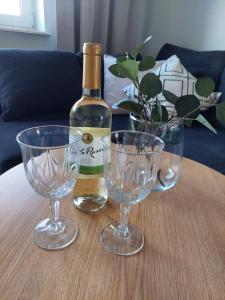 une bouteille de vin et deux verres à vin sur une table dans l'établissement Apartament Pod Bocianami, à Żelistrzewo