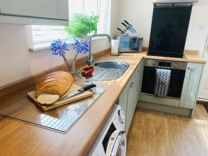 a kitchen counter with a sink and a loaf of bread at Atte Combe Cottage in Acomb +18 photos