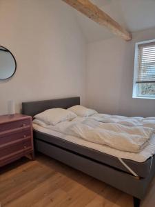 an unmade bed in a bedroom with a window at Hyggeligt lille byhus lige mellem havnen og bytorv in Ringkøbing