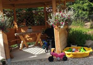 um jardim com uma mesa e um triciclo infantil em frente a uma madeira em STYLOWE APARTAMENTY W PORONINIE em Poronin