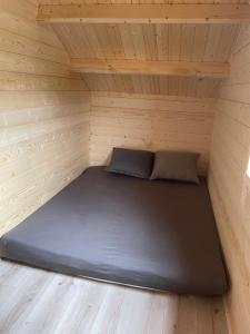 Łóżko w małym pokoju w drewnianym domku w obiekcie Osada Gardenia w Ślesinie