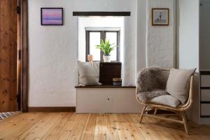 a living room with a chair and a window at Porthcurno Barns, The Big Barn - Spacious & cosy cottage, walk to Porthcurno beach, Pedn Vouder & Minack Theatre in Penzance