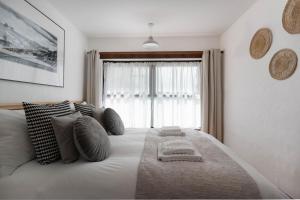 a bedroom with a large bed with pillows and a window at Porthcurno Barns, The Big Barn - Spacious & cosy cottage, walk to Porthcurno beach, Pedn Vouder & Minack Theatre in Penzance
