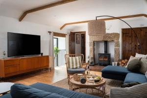 a living room with a blue couch and a tv at Porthcurno Barns, The Big Barn - Spacious & cosy cottage, walk to Porthcurno beach, Pedn Vouder & Minack Theatre in Penzance
