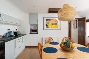 a kitchen with a table with a bowl of fruit on it at Porthcurno Barns, The Big Barn - Spacious & cosy cottage, walk to Porthcurno beach, Pedn Vouder & Minack Theatre in Penzance