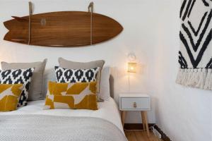 a bedroom with a bed with yellow and white pillows at Porthcurno Barns, The Big Barn - Spacious & cosy cottage, walk to Porthcurno beach, Pedn Vouder & Minack Theatre in Penzance