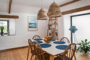 a dining room with a white table and chairs at Porthcurno Barns, The Big Barn - Spacious & cosy cottage, walk to Porthcurno beach, Pedn Vouder & Minack Theatre in Penzance