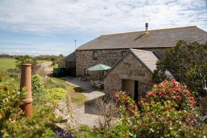 a stone building with a patio and a garden at Porthcurno Barns, The Big Barn - Spacious & cosy cottage, walk to Porthcurno beach, Pedn Vouder & Minack Theatre in Penzance