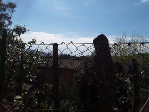 a barbed wire fence with a view of a house at Villetta a schiera nei pressi del mare in Livorno