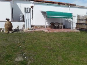 a white house with a patio with a green awning at Villetta a schiera nei pressi del mare in Livorno