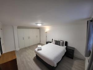 - une chambre avec un grand lit blanc et des armoires blanches dans l'établissement Cosy Apartment By Clapham South Underground!, à Londres