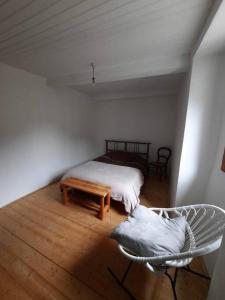 a bedroom with a bed and a chair and a table at Logement Sainte-Énimie in Sainte-Énimie