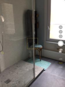 een douche in een badkamer met een stoel en een glazen deur bij Villa des sables in Duinkerke