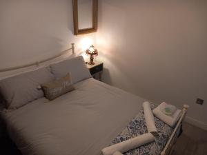 um quarto com uma cama branca e um candeeiro sobre uma mesa em Luxury holiday home, near beach em Southend-on-Sea