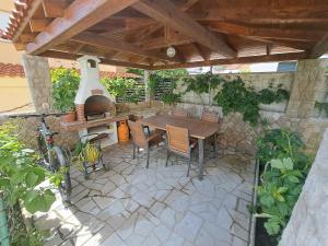 an outdoor patio with a table and a pizza oven at Apartments Fran I in Baška +29 photos