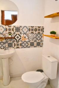 a bathroom with a white toilet and a sink at Villa Manga Rosa in Lençóis