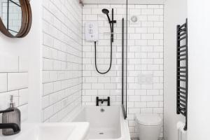 a white bathroom with a tub and a toilet at Porthcurno Barns, The Big Barn - Spacious & cosy cottage, walk to Porthcurno beach, Pedn Vouder & Minack Theatre in Penzance