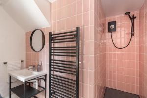 a bathroom with a sink and a shower with pink tiles at Porthcurno Barns, The Big Barn - Spacious & cosy cottage, walk to Porthcurno beach, Pedn Vouder & Minack Theatre in Penzance