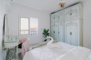 a white bedroom with a bed with a swan on it at Lovely Seaview Condo in Saba Pasha in Alexandria