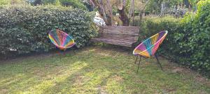 2 chaises et un banc en bois dans la cour dans l'établissement Gîtes le clos du verger, à Maurens 32 autres photos