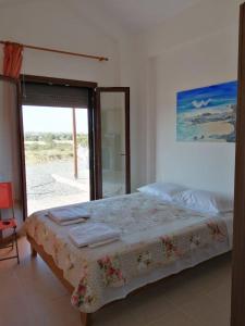 a bedroom with a bed and a large window at Red Village Limnos in Moúdhros