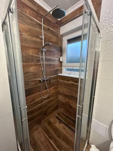 een badkamer met een douche en een houten muur bij Apartment Adrian in Kaštela