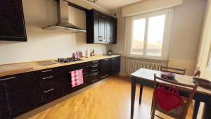 a kitchen with black cabinets and a table and a window at Chez Papa Appartamenti - Chez Coco in Ravenna