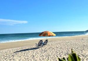 two chairs and an umbrella on a beach at Apartamento Vista ao Mar Maresias in Maresias +68 photos