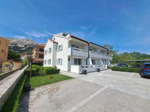 a white apartment building with a parking lot at Apartments Fran in Ba&scaron;ka