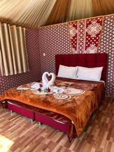 ein Schlafzimmer mit einem Bett mit zwei Schwänen darauf in der Unterkunft Areen camp, Wadi Rum in Wadi Rum
