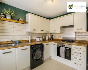 La cuisine est équipée de placards blancs et d'un lave-vaisselle. dans l'établissement LOW Price this winter 3 Bedroom House in Coventry - Sleeps 5 - With Free Unlimited Wi-fi, Driveway & Garden By Passionfruit Properties- 26WWC, à Coventry