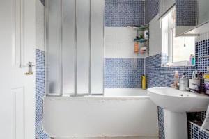 uma casa de banho em azulejos azuis com um lavatório e um chuveiro em Lovely and comfortable Home Stay in London em Londres