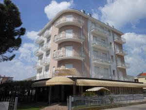 un edificio alto de color blanco con balcones y sombrilla en Hotel Jesolo Sand, en Lido di Jesolo