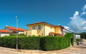 ein gelbes Haus mit Hecke vor einer Straße in der Unterkunft Villa Belgravia in Pula