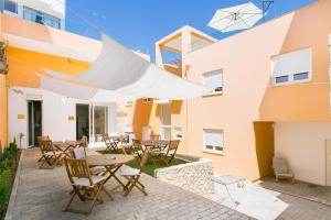 a patio with tables and chairs in front of a building at Casa Amarela Guesthouse in Albufeira