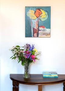 a vase of flowers on a table with a painting at La Maison Vague - Guest House in Marseille