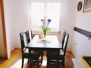 una mesa de comedor con un jarrón de flores. en FoREST Heritage Apartment, en Hreljin
