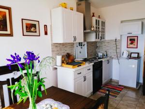 una cocina con armarios blancos y una mesa con flores púrpuras en FoREST Heritage Apartment, en Hreljin