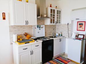 cocina con armarios blancos y fogones negros en FoREST Heritage Apartment, en Hreljin