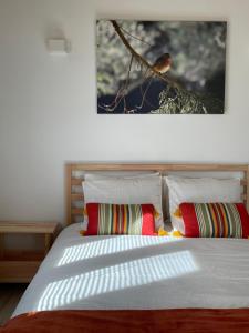 1 cama con 2 almohadas y una foto en la pared en Casinha Rubiães en Paredes de Coura