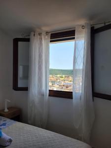 una camera da letto con una finestra con tende bianche e un letto di Casa Clara a Bari Sardo