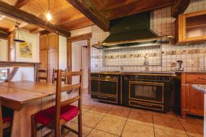 a kitchen with a stove and a wooden table at Longère bressane de la Verne in Cormoz