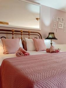 una camera da letto con un grande letto con coperte e cuscini rosa di Olyna’s Apartment N.S Preveza a Néa Sampsoús