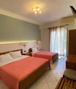 a hotel room with two beds and a window at Paradosi Rooms in Igoumenitsa