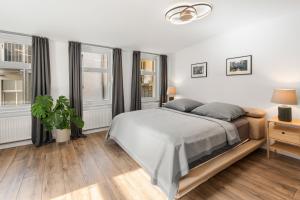 ein weißes Schlafzimmer mit einem Bett und zwei Fenstern in der Unterkunft GreatStay - Tieckstr.3 Loft for up to 7 people in Berlin