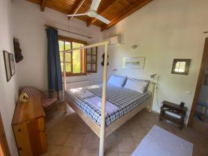Jenny's Guesthouse! في أرتيميدا: غرفة نوم بسرير وسقف خشبي