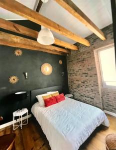 a bedroom with a large bed with a brick wall at Maison Capbreton à 4 min des plages in Capbreton